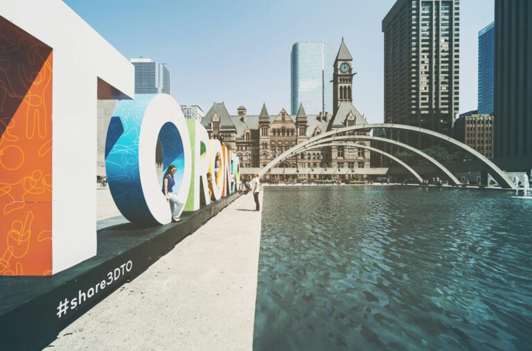 Toronto sign at Nathan Phillips Square with Old City Hall and water fountain — representing Canada work visa opportunities for skilled professionals from Asia and GCC.